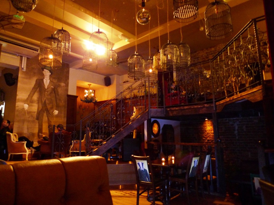 A two-level bar with distinctive birdcage pendant lights and stylish seating, showcasing how design influences atmosphere.