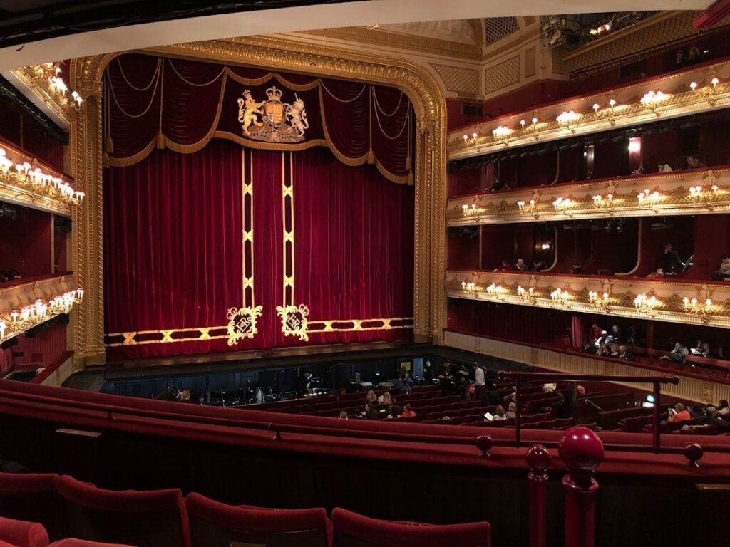 Ornate historic theater interior with red curtain and multiple balconies