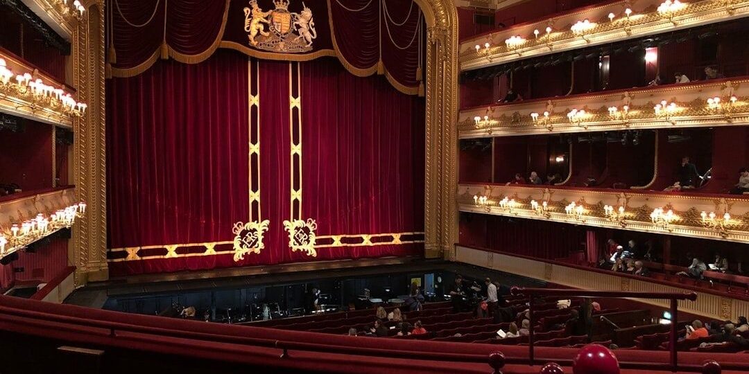 Ornate historic theater interior with red curtain and multiple balconies