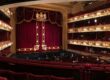 Ornate historic theater interior with red curtain and multiple balconies