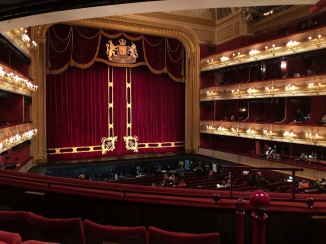 Ornate historic theater interior with red curtain and multiple balconies