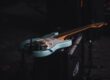 Blue electric guitar resting on audio equipment in a dark setting