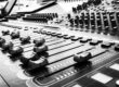 Close-up black-and-white view of a professional audio mixing console