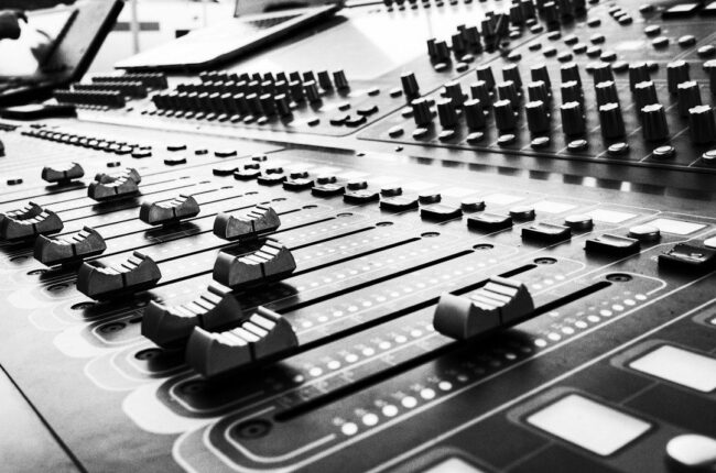 Close-up black-and-white view of a professional audio mixing console